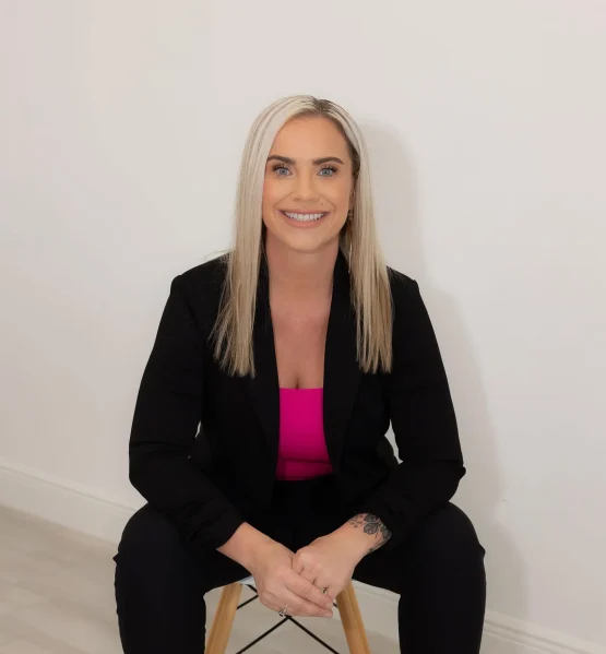 How Semaglutide and Tirzepatide Work for Weight Loss Professional woman seated, smiling confidently in a black blazer with a bright pink top.